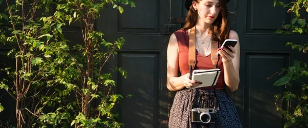 A journalist standing outside looking at her phone.